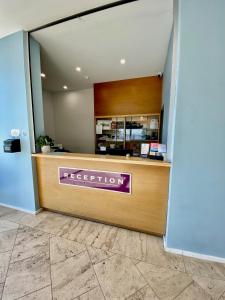 パースにあるOcean Beach Hotelの紫の看板が貼られたフロントデスク