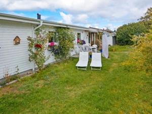a yard with white chairs and a house at 9 person holiday home in Skummeslövsstrand in Skummeslövsstrand