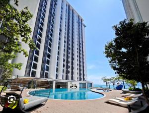 a large building with a swimming pool next to the ocean at The ocean city view in Kota Kinabalu