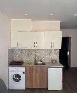 a kitchen with white cabinets and a washing machine at Aqua Batumi 44 in Batumi