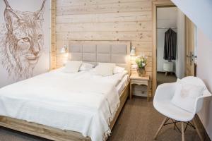 a bedroom with a white bed and a white chair at DW Boguń Pokoje i Apartamenty in Białka Tatrzańska