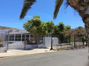 a building with a fence in front of a street at La Palmita de Canarias in Agaete