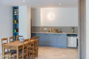 a kitchen with a wooden table and blue cabinets at La maison du Sophora grande maison 3 chambres in Saint-Didier-de-Formans +23 photos