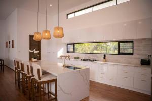 a kitchen with white cabinets and a kitchen island with chairs at Heaven Retreat with Minigolf, pool, fire pit, BBQ in Nadi