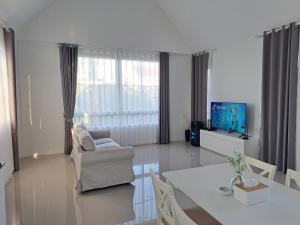 a living room with a table and a couch and a tv at ร็อคกี้ พูลวิลล่า เขาใหญ่ Rocky Pool Villa Khaoyai in Pong Talong