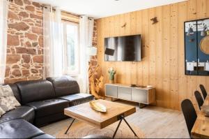 a living room with a leather couch and a tv at Les Boisés à Kaysersberg+ 1 place de parking in Kaysersberg