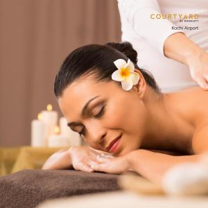 a woman with a flower on her head laying on a towel at Courtyard by Marriott Kochi Airport in Nedumbassery +37 photos