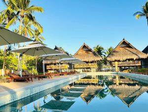 a pool at a resort with umbrellas and tables at Station One Beach Resort in El Nido
