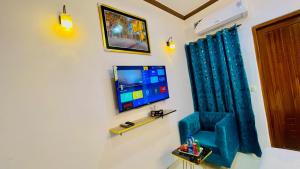 a room with a tv and a blue chair at Go Guest House Lahore in Lahore