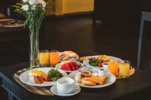 a breakfast table with plates of food and orange juice at THEE Kashatharn by TH District in Chiang Mai