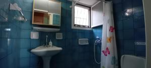 a blue tiled bathroom with a sink and a shower at Aperando in Tolo
