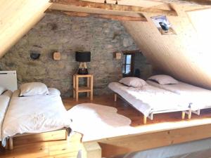 two beds in a room with a stone wall at Maison typique rénovée 4 CHBR lac d'Oô Peyragudes in Oô