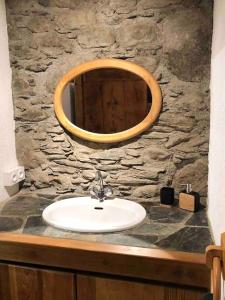 a bathroom with a sink and a mirror on a stone wall at Maison typique rénovée 4 CHBR lac d'Oô Peyragudes in Oô