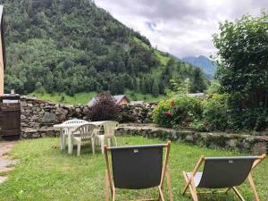 two chairs and a table in a yard with mountains at Maison typique rénovée 4 CHBR lac d'Oô Peyragudes in Oô