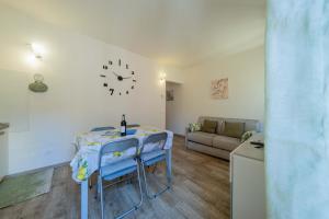 sala de estar con mesa, sillas y reloj en ApartmentsGarda - Residenza Emanuele, en Torri del Benaco