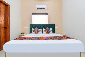 Un dormitorio con una gran cama blanca con almohadas de colores. en FabHotel Prince 24, en Mohali