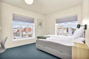 a white bedroom with a bed and two windows at Central Guest House - Bedroom with en suite Bathroom in Stavanger