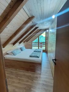 a bed in a room with a wooden ceiling at Vikendica Ana in Šipovo