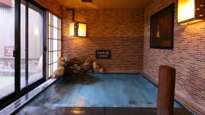 a swimming pool in a room with a brick wall at Dormy Inn Takamatsu in Takamatsu