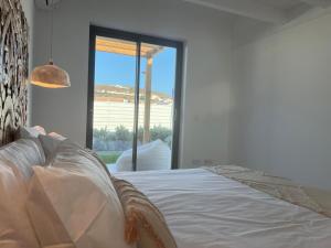 a white bed in a room with a large window at Casa Barranco in Carrapateira