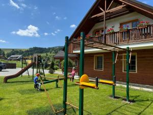 two children playing on a playground in front of a house at Apartmány Roháče in Zuberec