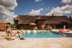 a woman sitting in front of a house with a swimming pool at Apartament z wanną wolnostojącą in Stare Miasto