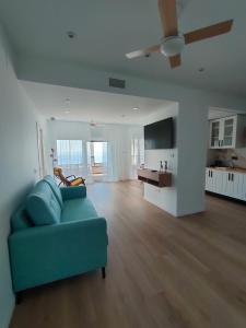 a living room with a blue couch and a kitchen at Seafront Homes in Castillo de BaÃ±os