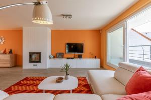 a living room with orange walls and a couch and a tv at Huswell - Cozy seaside apartment with sunny terrace in Blankenberge +16 photos