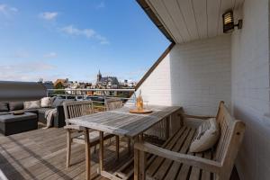 a balcony with a wooden table and chairs on a roof at Huswell - Cozy seaside apartment with sunny terrace in Blankenberge