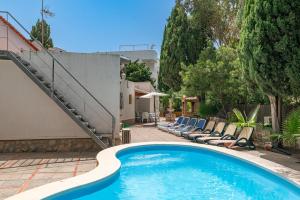 a swimming pool with lounge chairs next to a house at Villa Minerva by Sealand Villas in Alcudia