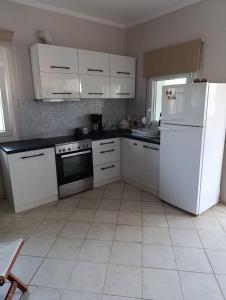 a kitchen with white cabinets and a white refrigerator at Villa savvas in Paralía Avdhíron +6 photos