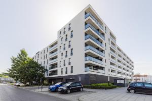 ワルシャワにあるSuperApart Światowida 16 - Białołęka z parkingiemの大きな白い建物と駐車場に駐車された車