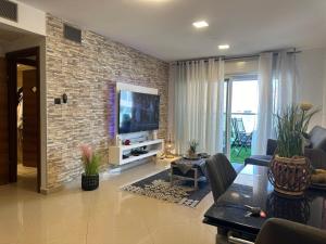 a living room with a television and a brick wall at מיני סוויטה לה פלמורה in Eilat