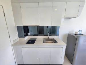 a white kitchen with a sink and a refrigerator at Nice apartment in Pattaya Central