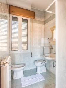 a white bathroom with two sinks and a toilet at Hotel Clodia in Chioggia