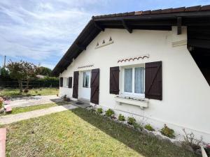 a white house with brown doors and a yard at Cabane Meysouet-maison refaite à neuf vélo Bourg in Mimizan