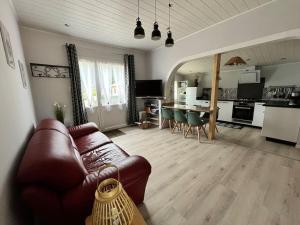a living room with a leather couch and a kitchen at Cabane Meysouet-maison refaite à neuf vélo Bourg in Mimizan +30 photos