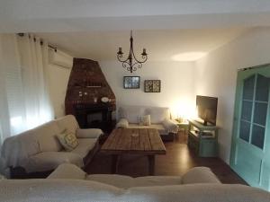 een woonkamer met banken, een tafel en een tv bij CHIBITEL Alojamiento Rural in Córdoba