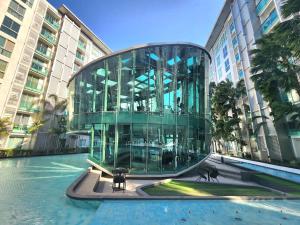 a building with a glass facade and a pool of water at Nice studio comfortable in Pattaya Central