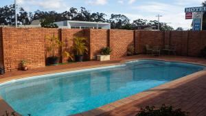 a swimming pool in front of a brick wall at Yambil Inn in Griffith