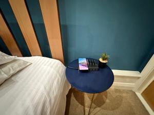a blue table next to a bed with a book at Lovely modern Studio in the Heart of City Centre in Nottingham