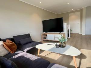 una sala de estar con un sofá y una mesa en Bo moderne på Falkum med utsikt, en Skien
