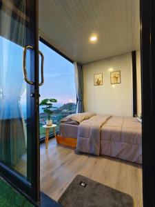 a bedroom with two beds and a large window at ชาร์จแบต ภูทับเบิก in Ban Muang Baeng
