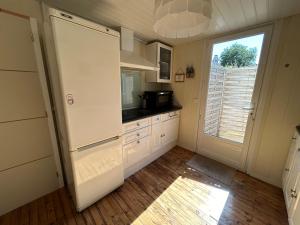 a kitchen with a white refrigerator and a window at Maison MAHECO in Gujan-Mestras