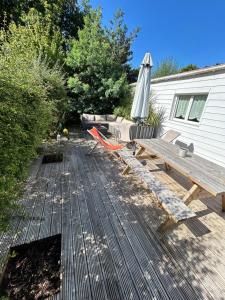 a wooden deck with a picnic table and an umbrella at Maison MAHECO in Gujan-Mestras