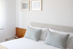 Un dormitorio con una cama blanca con almohadas azules y blancas. en Bruma Marina, en A Guarda