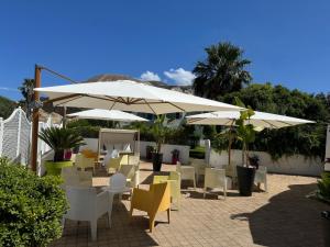 a patio with tables and chairs and umbrellas at Il Caimano B & B, con piscina dall'11 Luglio al 31 Agosto in Vulcano