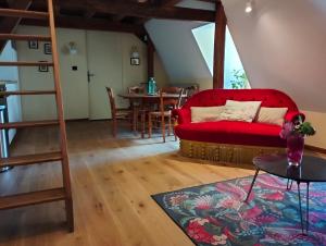 a living room with a red couch and a table at Le logis Bodard Appartement centre ville dans un hôtel particulier XIVeme avec parking et locale vélo in Chinon