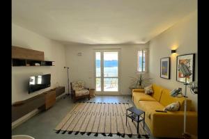 a living room with a yellow couch and a television at Aurora's Home Lake View Apt in Argegno