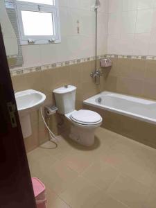 a bathroom with a toilet and a tub and a sink at Hostel Maral in Mawāliḩ